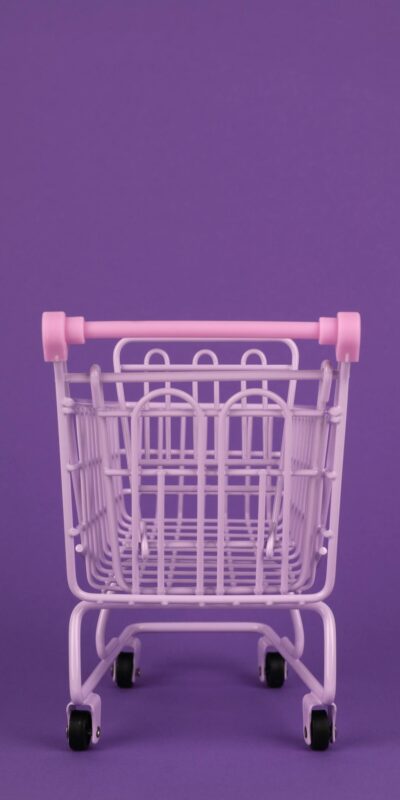Minimalist image of a pastel pink shopping cart against a vibrant purple background, ideal for abstract concepts.