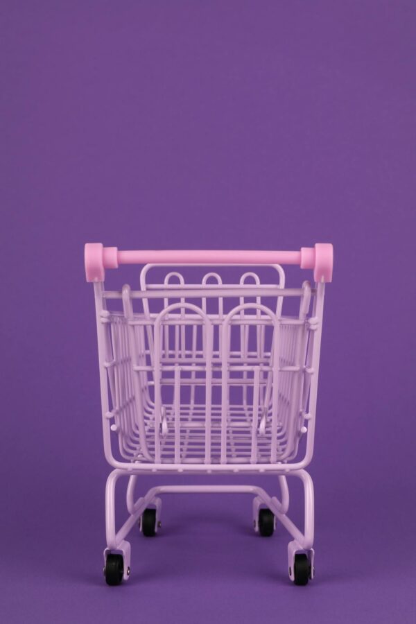 Minimalist image of a pastel pink shopping cart against a vibrant purple background, ideal for abstract concepts.